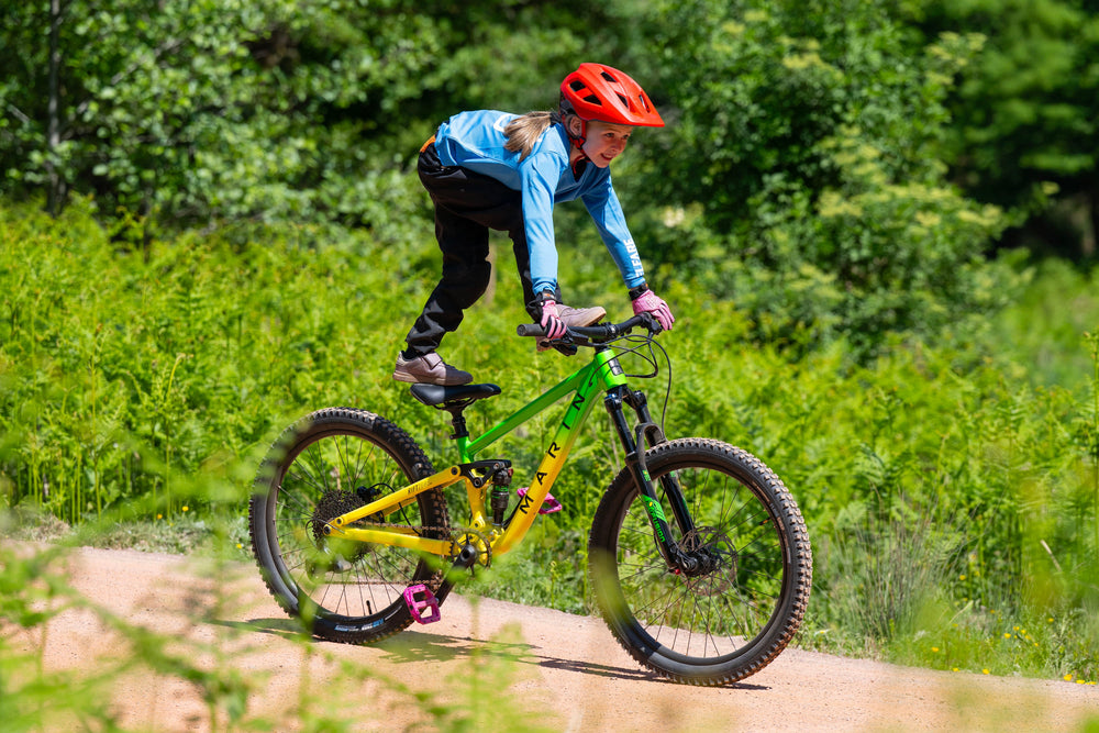 young girl stands on bike