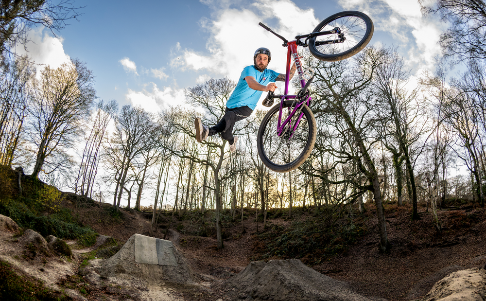 Man riding a dirt jump bike with tricks 