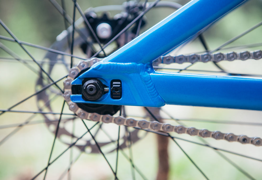 Close-up of a bicycle chain and gear system with a blue frame.