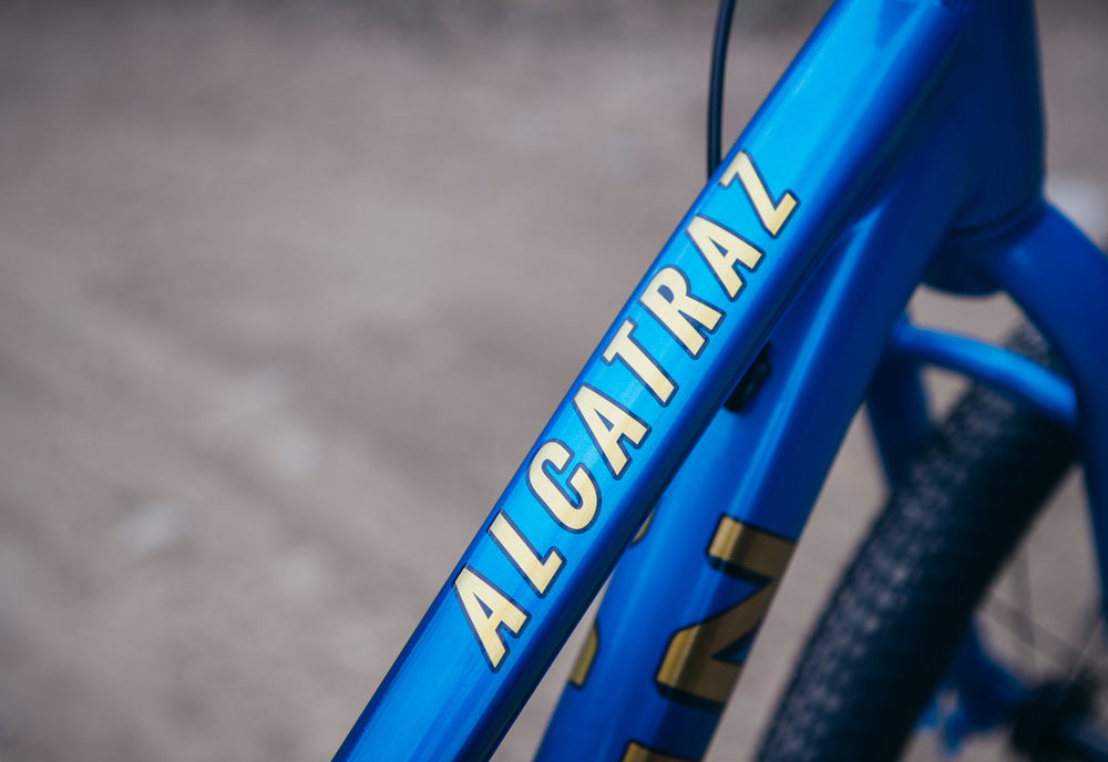 Blue bicycle frame with 'ALCATRAL' branding on a blurred background