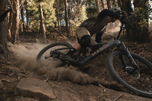 Man riding an ebike downhill on a dusty trail