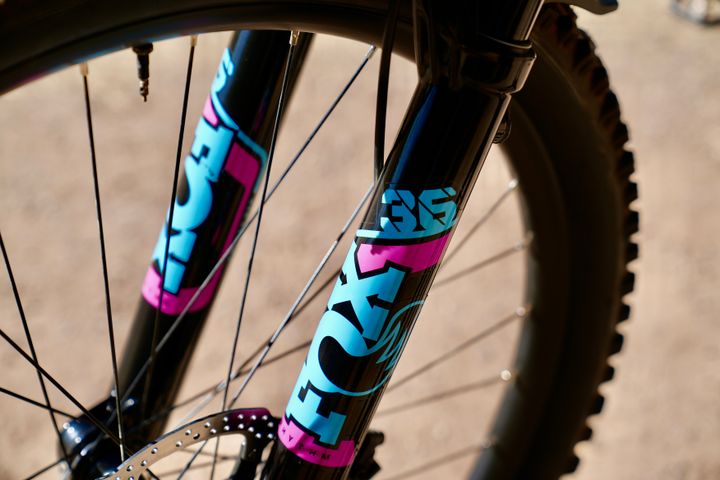 Close-up of a bicycle fork with colorful branding on a blurred background