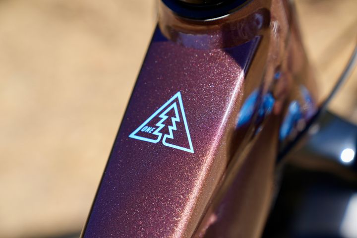 Close-up of a purple and gold product with a logo on a blurred background