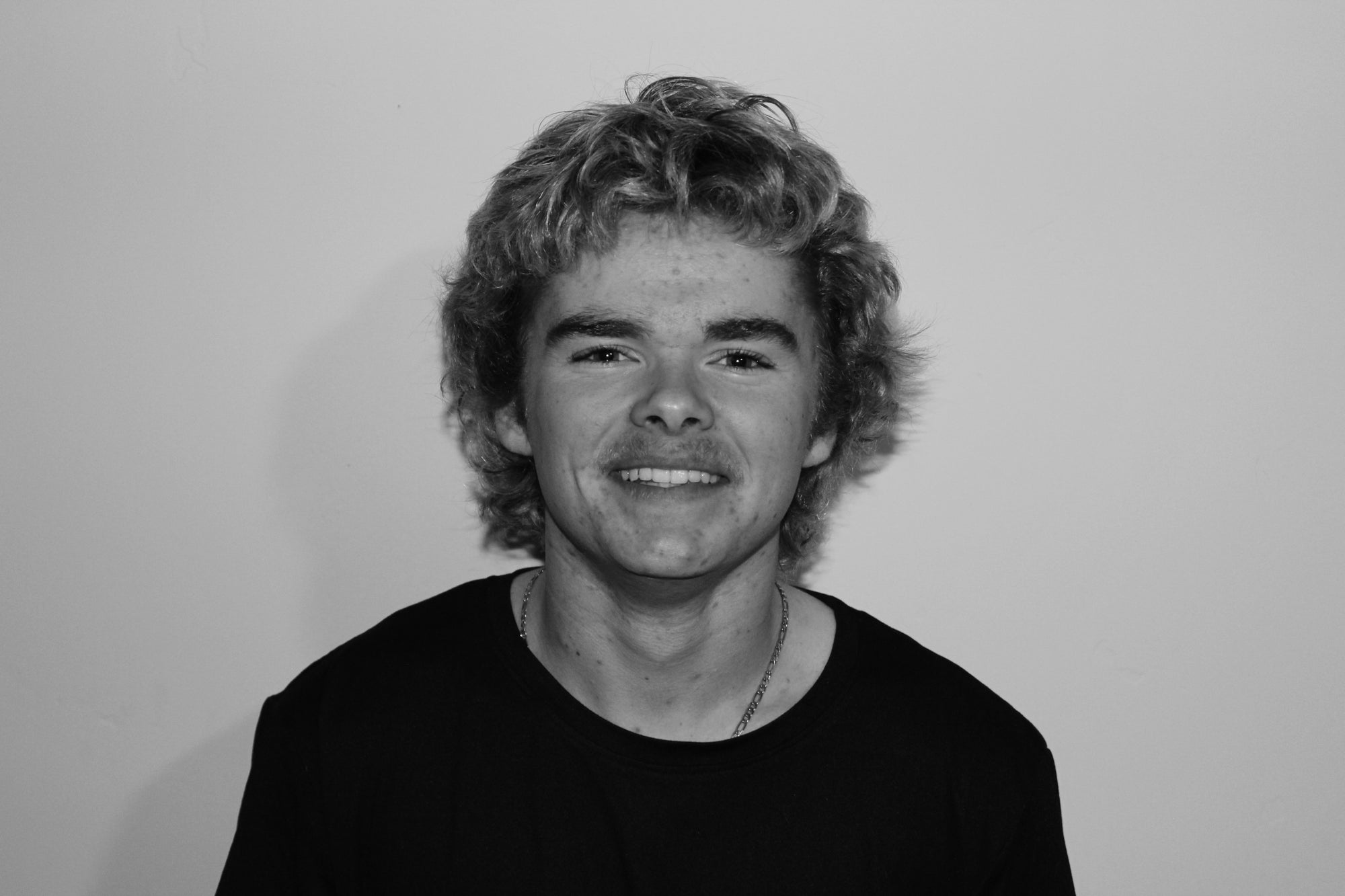 Black and white photo of a person with curly hair against a plain background