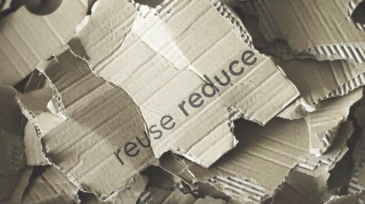 An image of some cardboard boxes ready for recycling with the words 'reuse reduce' written on them