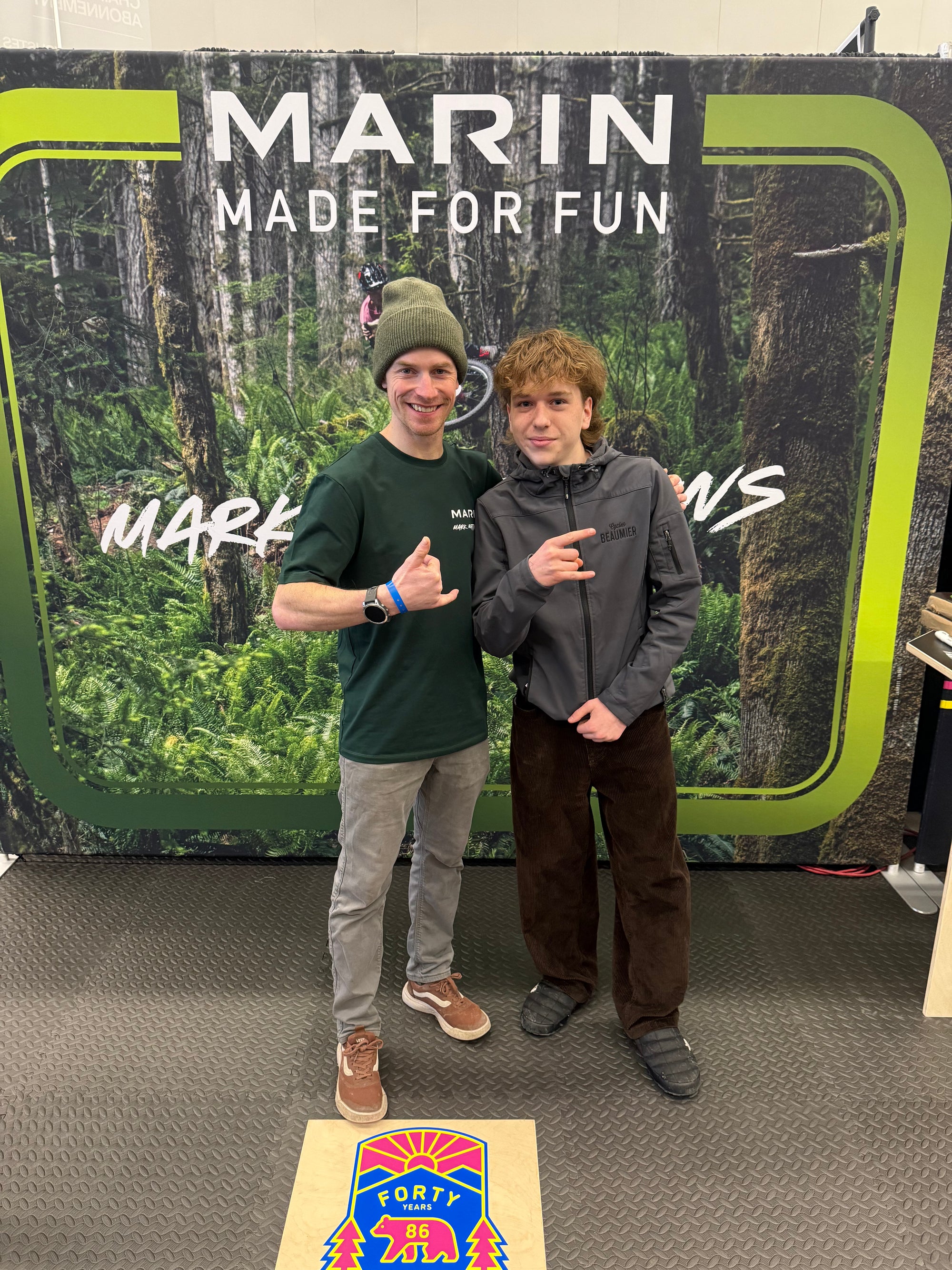 Two people posing in front of a 'Marin Made for Fun' branded backdrop.