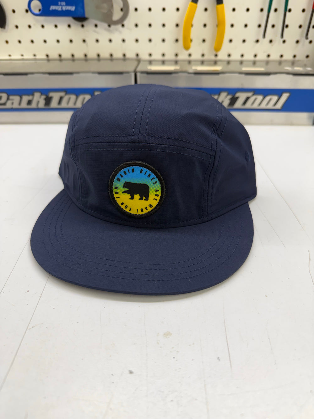 Navy blue cap with a logo on a white surface with tools in the background