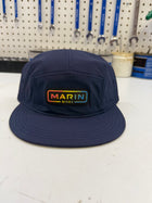 Navy blue cap with 'Marin Bikes' logo on a white surface with tools in the background