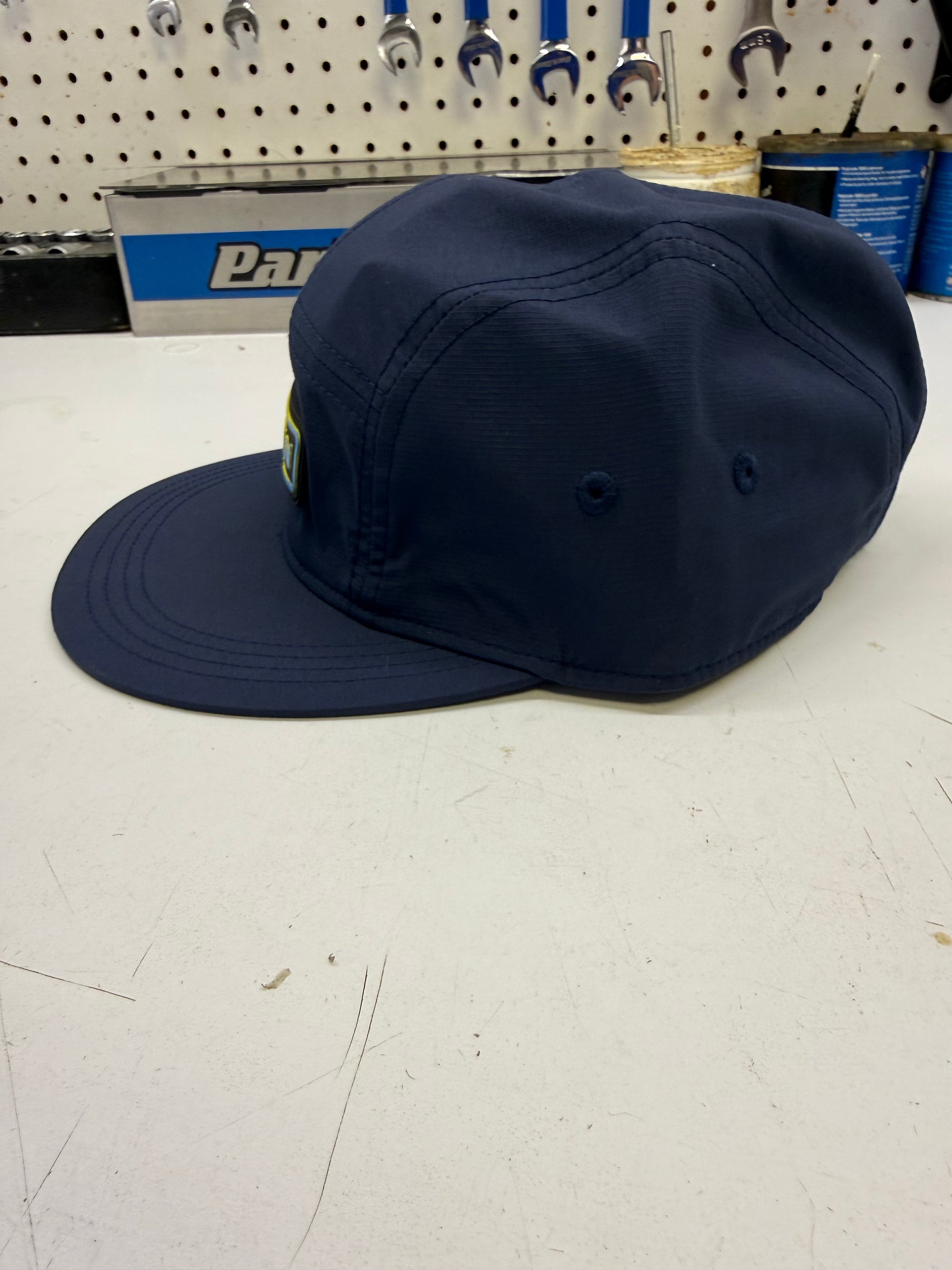 Navy blue cap on a white surface with tools in the background