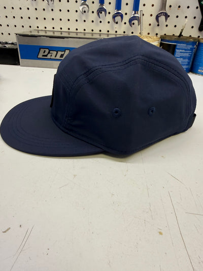 Navy blue cap on a white surface with tools in the background