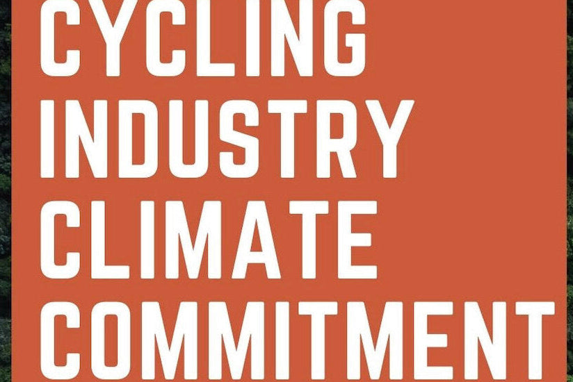 An overhead drone shot of a large forest with green, leafy trees with the words 'we commit to the cycling industry climate commitment' overlayed on the image