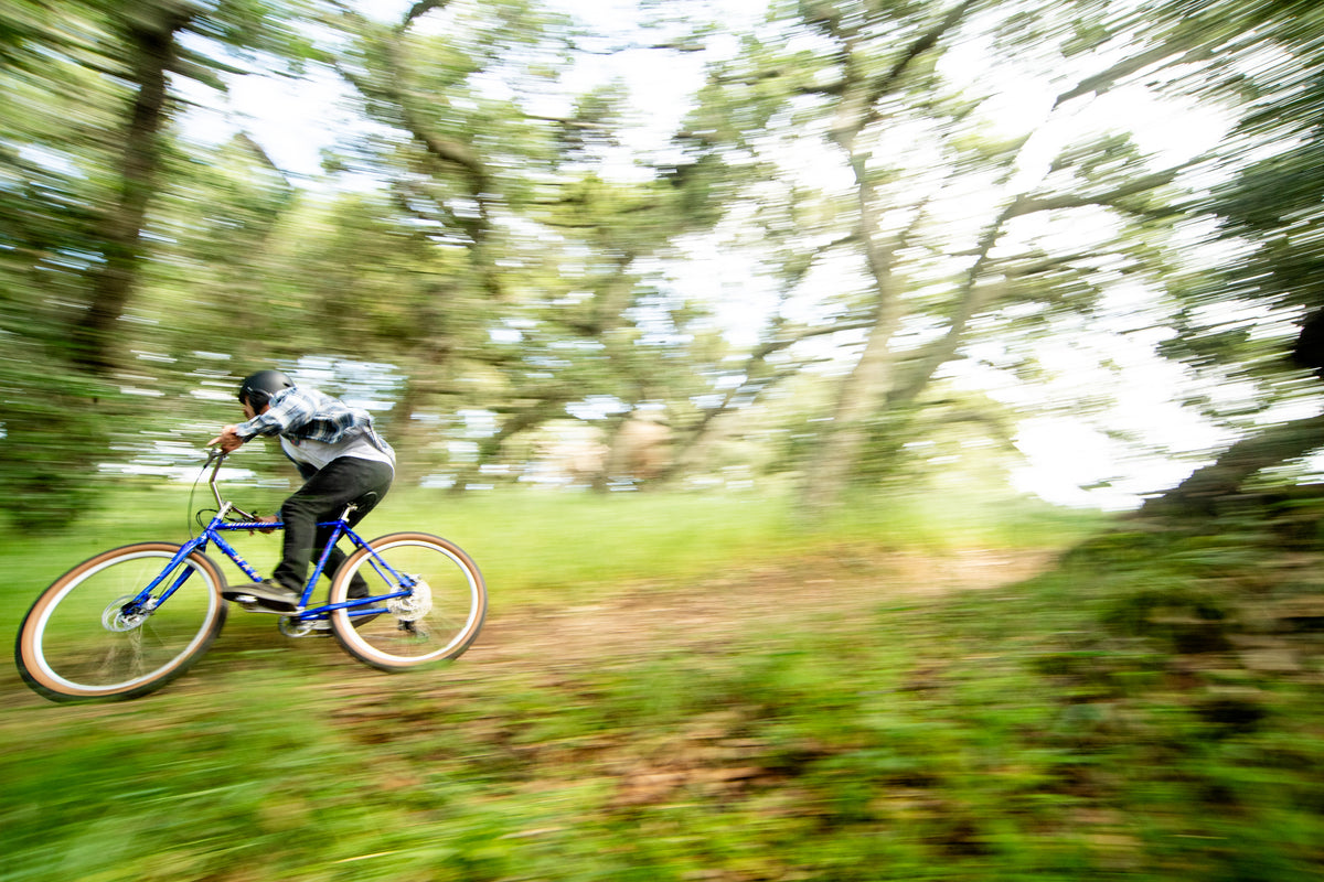 Person riding a blue bicycle through a forest with motion blur effect