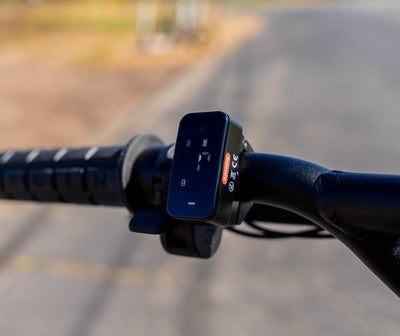Close-up of a handlebar with a control panel on a blurred road background