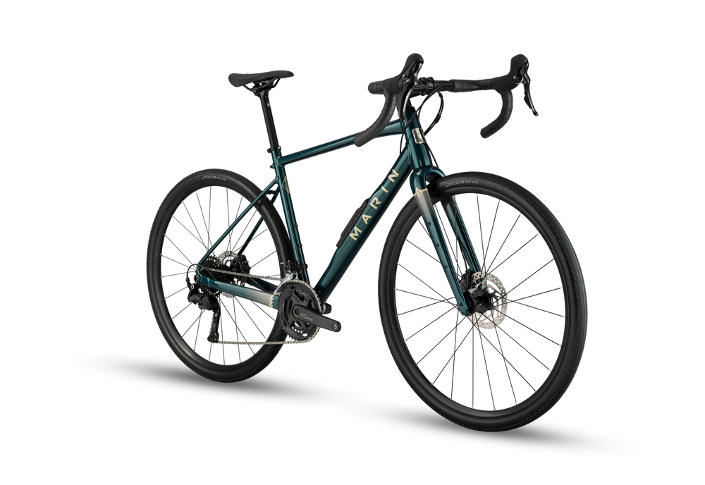 A gravel bicycle with a dark teal-green frame, black handlebars, and black wheels, shown from a three-quarters angle on a white background with a soft shadow.