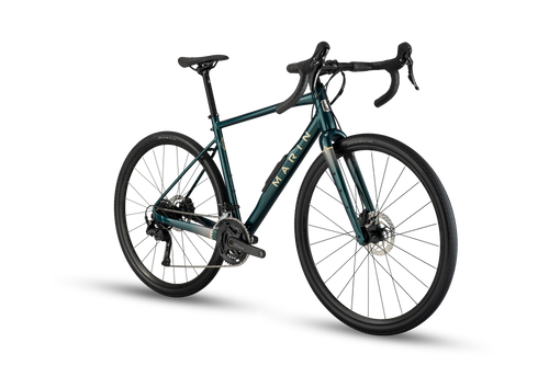 A gravel bicycle with a dark teal-green frame, black handlebars, and black wheels, shown from a three-quarters angle on a white background with a soft shadow.
