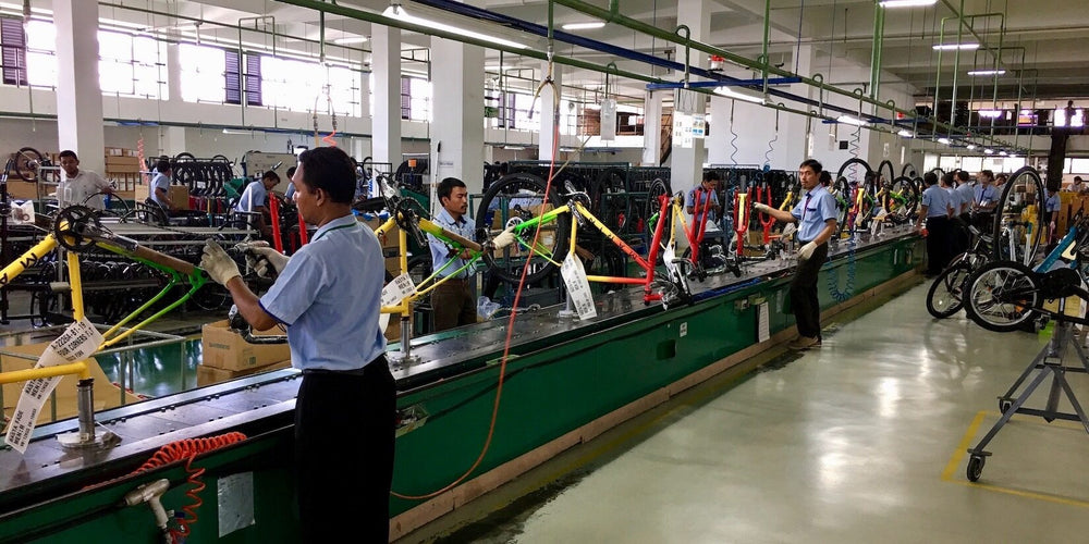 An image of a Marin Bikes bicycle assembly line in a factory with employees performing different tasks on multiple bikes which are on a conveyor belt