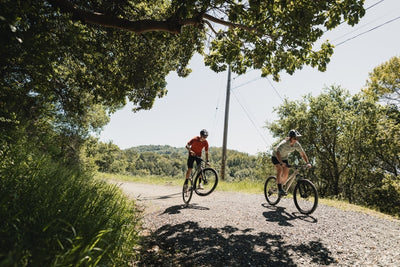 Couple ride bikes along a gravel track
