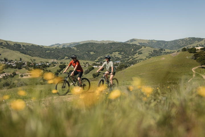 Couple ride bikes along a gravel track in the mountains