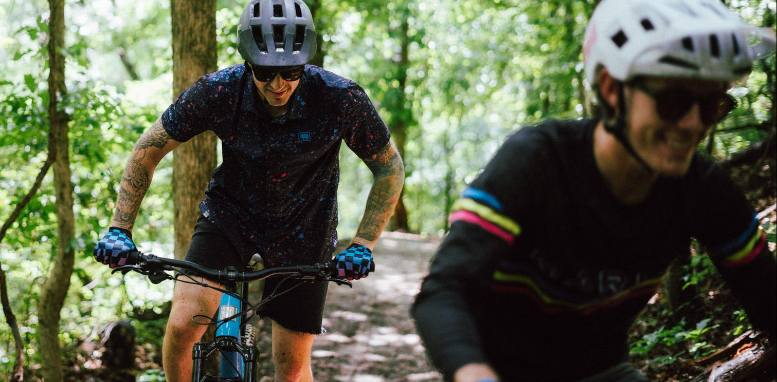 Two mountain bikers riding through a forest on a trail.