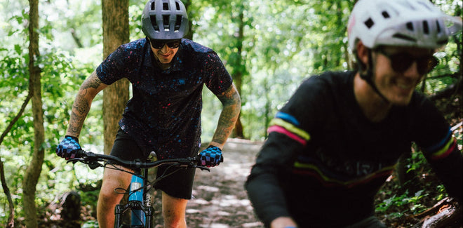 Two mountain bikers riding through a forest on a trail.