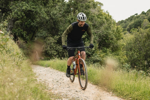 Man rides along a gravel track in woodland