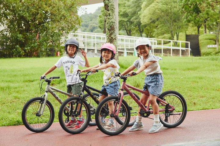 Three children with bicycles in a park setting