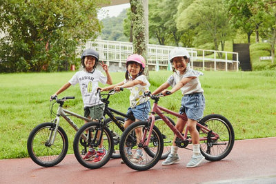 Three children with bicycles in a park setting