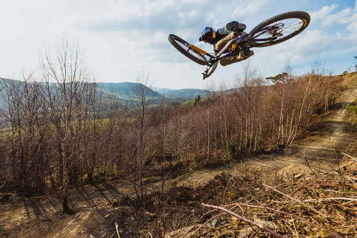 Biker in mid-air performing a stunt on a mountain bike with a scenic background