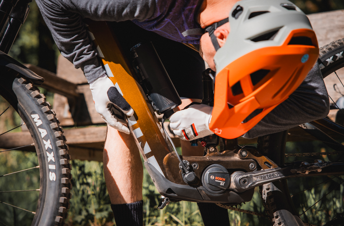 Person on a mountain bike with an orange helmet and Mavic tires in a forest setting