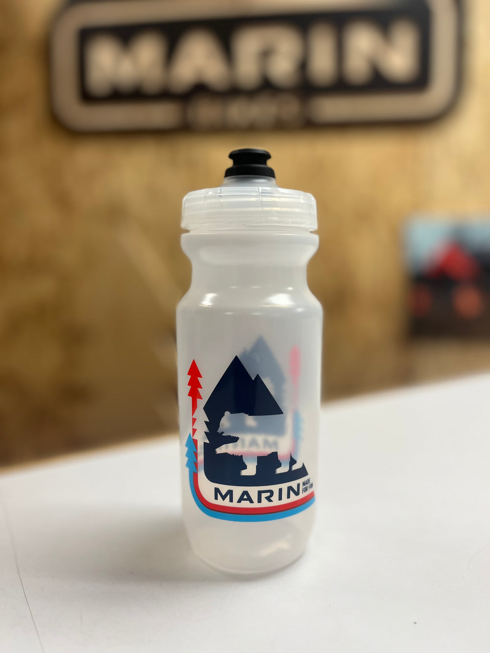 Clear water bottle with a bear and mountain design on a white surface, with 'Marin' branding in the background.